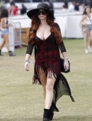 Phoebe Price flashes a peace sign as she wears and small red dress revealing ample cleavage, a black hat and large sunglasses on day one of week two of the Coachella Music Festival in Indio