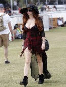 Phoebe Price flashes a peace sign as she wears and small red dress revealing ample cleavage, a black hat and large sunglasses on day one of week two of the Coachella Music Festival in Indio