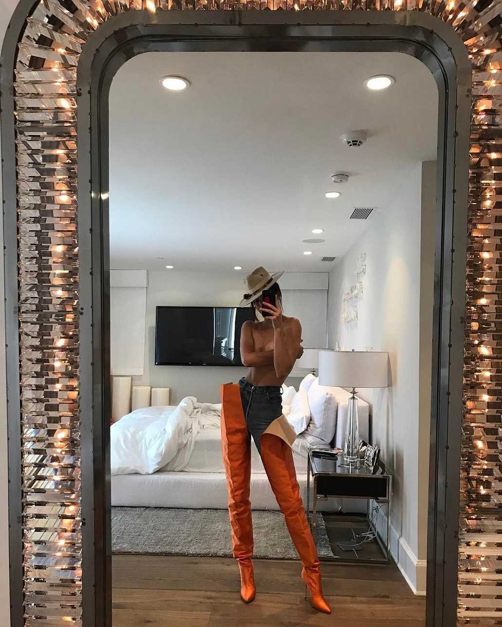 In the picture, Kendall pairs jeans with waist-high orange boots, a hat, and literally nothing else. Kendall captioned the picture, "Playing dress up."